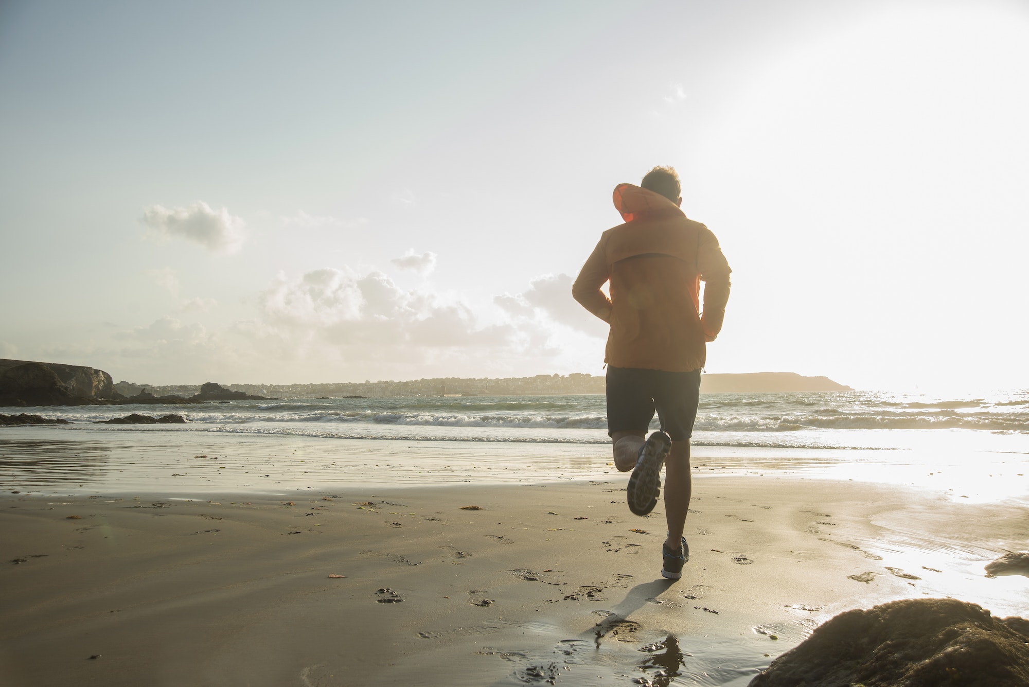 Mature man running on sand, along coastline